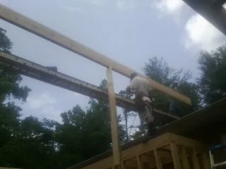 Carpenter setting a ridge beam over a new addition frame — Ice Dam Removal by Roofing Brothers in Redford