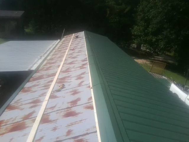 Old rusted panels beside newly installed green metal roofing — Wind Damage Roof Repair by Roofing Brothers in Redford