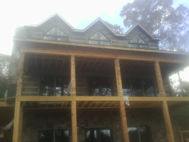 Dormers and porch framing on a large log home under construction — Roof Coating work by our crew in Redford