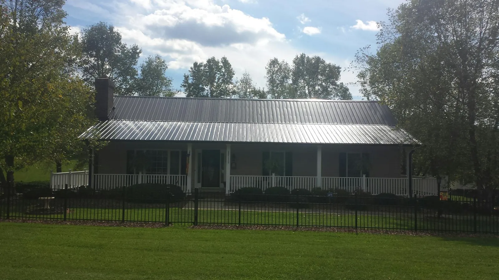 Gray metal roof on a brick ranch with a full width front porch — Gutter Guard Installation work by our crew in Redford